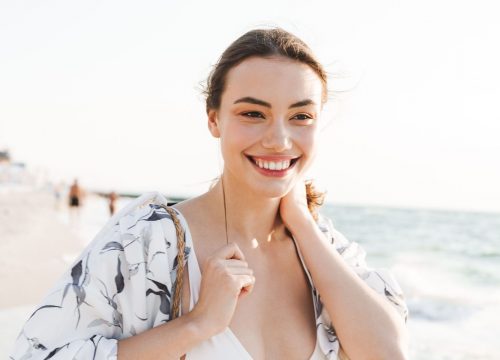Happy woman at the beach after receiving Facials